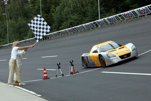 Karl Mauer überquert im Opel Eco Speedster am
Sonntag, 27. Juli 2003, die Ziellinie auf der Opel
Hochgeschwindigkeitsstrecke in Dudenhofen, während
Vorstandsmitglied Klaudia Martini die Zielflagge schwenkt.