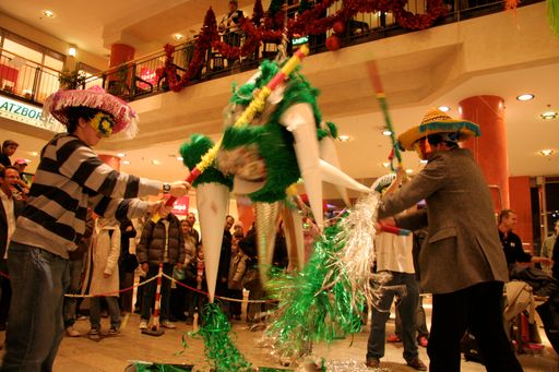  Kunden des Generali-Centers schlagen mit verbundenen Augen auf die "Pinata" bis diese zu Bruch geht und aus ihrem Inneren viele Geschenke (Gutscheine) purzeln.