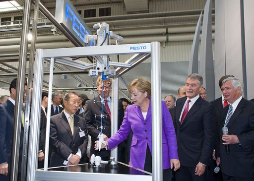 Vorschau Bild von Die deutsche Bundeskanzlerin Angela Merkel erprobt den Prototypen eines bionischen Greifers von Festo, der als Novum in der Automation auch zerbrechliche oder unregelmäßig geformte Gegenstände, wie z.B. eine Glühlampe adaptiv greifen und sicher absetzen kann.