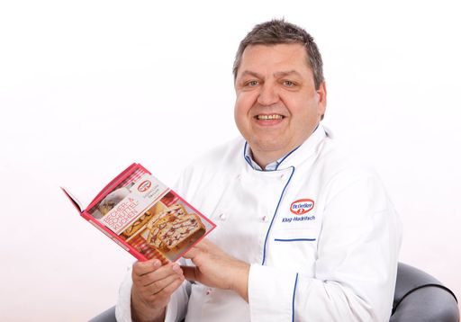 Der Dr. Oetker Konditormeister schmökert in seinem Backbuch. Vielleicht findet sich darin bald auch Ihr Rezept?