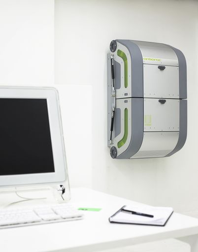  Der armarac(tm) Serverschrank hängt neben einem Arbeitsplatz im Büro an der Wand.