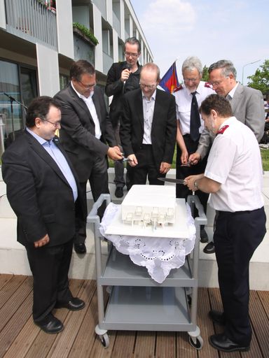 Im Bild v.l.n.r: Pfarrer Mag. Michael Chalupka (Direktor Diakonie Österreich), DSA Daniel Zimmermann (Bereichsleiter Haus Erna), Kurt Gutlederer (Abteilungsleiter Wiener Wohnungslosenhilfe), Oberst Franz Boschung (Chefsekretär Heilsarmee Schweiz), Ing. Heinz Lehner (Bezirksvorsteher 21. Bezirk) und Hans-Marcel Leber (Geschäftsführer Heilsarmee Österreich) beim feierlichen Anschnitt der Torte in Hausform.