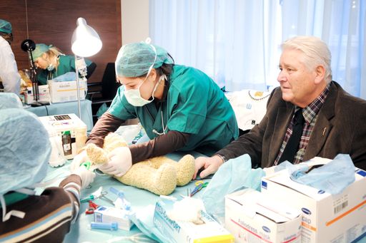 Ärztekammerpräsident Walter Dorner beobachtet ganz genau, wie ein Kind seinen Teddybären verarztet.