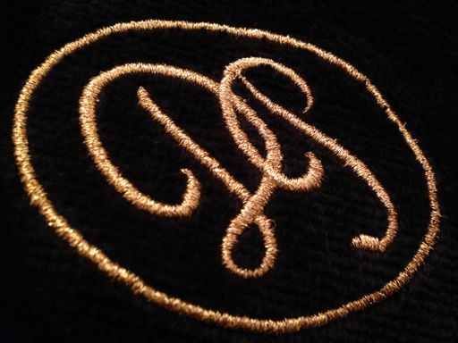 Stickerei auf einem schwarzen Bademantel, Monogramm bestickt in
Gold.