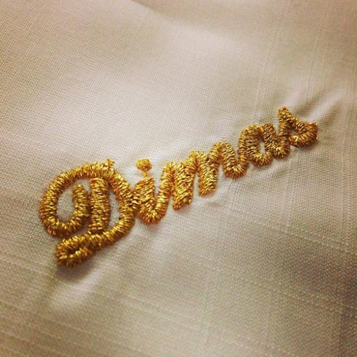 Vorschau Bild von Gestickter Namen auf einem Stoff mit goldenem Metallgarn.