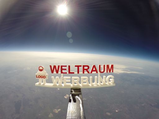  Weltraum Werbung aus ca. 30 000m Höhe. Logo wird fotografiert.
Stratosphärenflug mit einem Ballon, im Hintergrund die Erde. Werbung
im All.