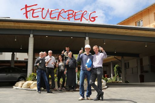 Geschafft - 5,3 Millionen Euro in 10 Wochen:
Projektleiter Thomas Freunschlag (Architekten Ronacher, vorne rechts
mit Helm) und Feuerberg-Eigentümer Erwin Berger (vorne ganz rechts)
stoßen unter dem Jubel des Feuerberg-Teams auf den Abschluss der
8ten Feuerberg-Baustufe an.