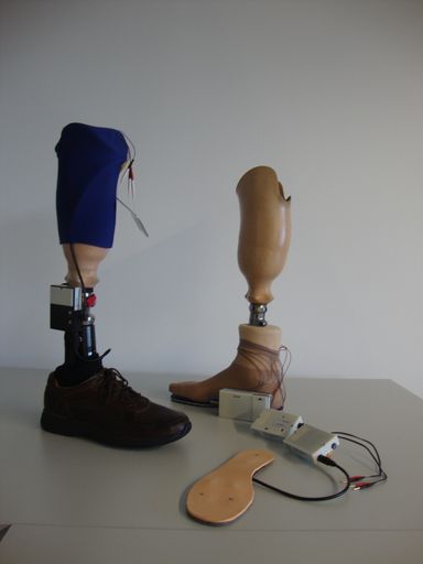  Unterschenkel-Prothese mit Kniekappe und das
installierte System, die Unterschenkelprothese rechts mit Stimulator
im Testaufbau, sowie eine Sensorsohle mit Transmitter und
Stimulator.