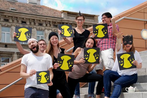  Eine Gruppe motivierter Menschen hält Schilder mit
dem Logo der Europäischen Theaternacht in Händen.