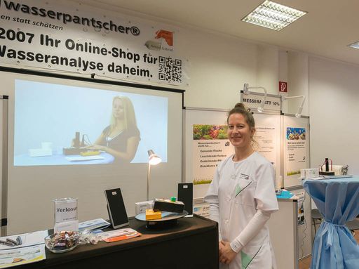 Vorschau Bild von Am Messestand der Firma Wasserpantscher kann eine
mitgebrachte Wasserprobe selbst gemessen werden, die Wasserpantscher
helfen dabei, im Bild Ing. Nicole Halanek, die Laborinhaberin.