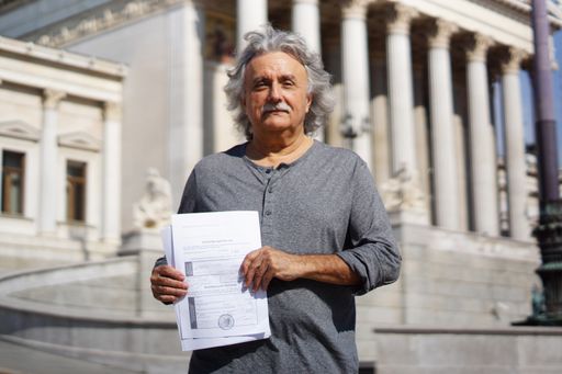 KPÖ PLUS-Spitzenkandidat Mirko Messner mit
gesammelten Unterstützungserklärungen vor dem Parlament.