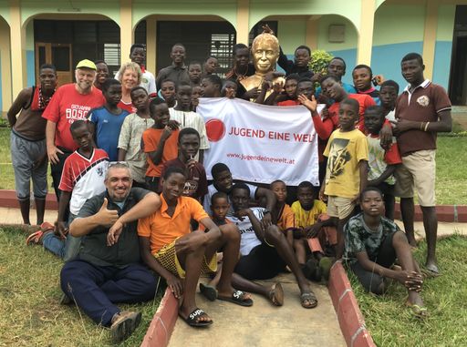 Jugend Eine Welt Vorsitzende Monika Mlinar mit
ehemaligen Straßenkindern und Projektpartnern vor Don Bosco Statue
in Ghana