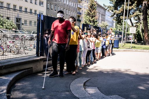 Vorschau Bild von Alphonse Lekanga und Manuel Wagner sind als ein
Künstlerteam mit den Kindern auf dem Weg zum Speisesaal. Auch das
gemeinsame Essen ist ein zentraler Teil im Rahmen der Mel-low Yellow
Aktionstage.