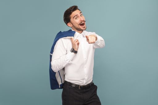 wondered and pointing finger at camera portrait of
handsome bearded businessman in white shirt holding his blue jacket,
with smart watch. Indoor studio shot, isolated on light blue
background