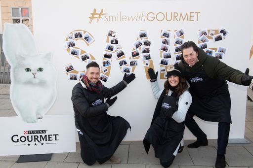 Vorschau Bild von Andi Moravec, Maggie Entenfellner und Daniel
Serafin (v.l.n.r.) vor der fertig beklebten GOURMET Smile-Wall