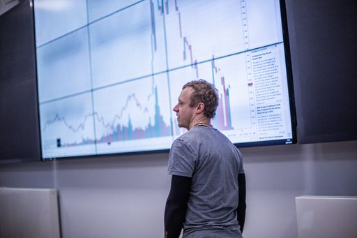 Vorschau Bild von Studierender vor Videowall mit Finanzzeitreihe
