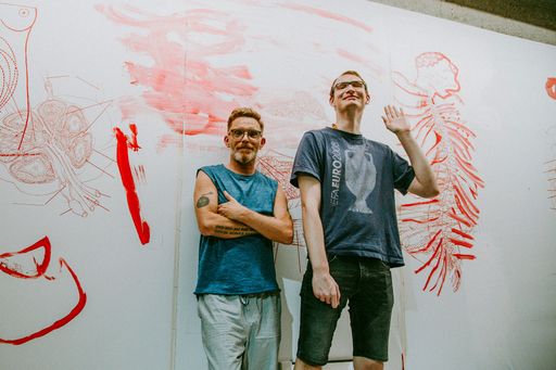 TOMAK, Leiter des Kunstprojektes Aktion 11 und
Christian Öllinger, Künstler, Die Kunstwerkstatt │Diakoniewerk vor
dem Fries im Aktionsraum LINkZ. (v.l.n.r.)