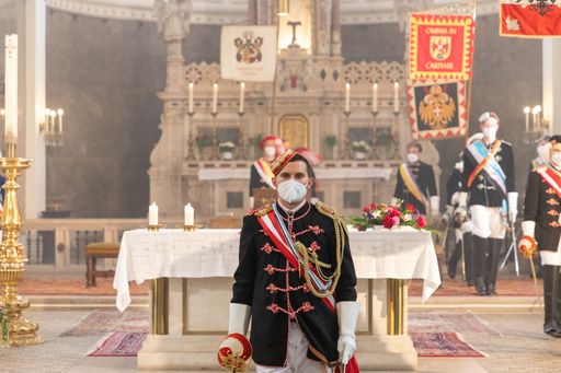  Der MKV Jugendobmann steht in der traditionellen
Festkleidung der katholischen Verbindungen mit Blickrichtung zur
Kamera vor dem Altar. Im Hintergrund sind unscharf weitere MKV
Verbindungsstudenten und Standarten zu sehen.