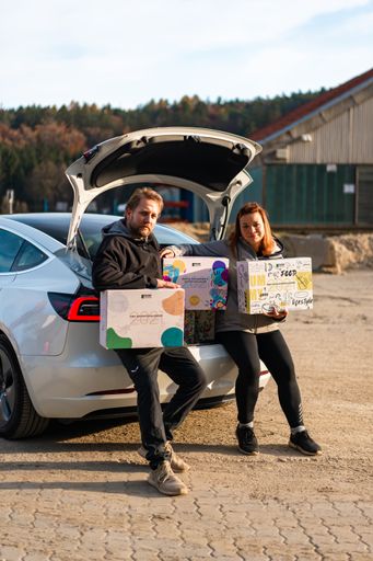 Vorschau Bild von Tesla mit Hanf Adventskalendern und den Gründern des Hanf
Magazins Lucas und Julia