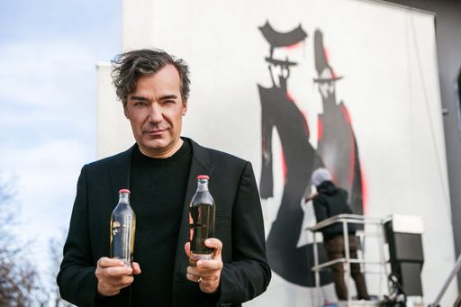 Vorschau Bild von Almdudler Sprudelfabrikant Heribert Thomas Klein
mit Almdudler Golif Edition vor Almdudler Haus mit Golif Gemälde