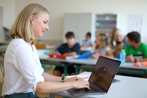 Lehrerin am Laptop vor Klasse