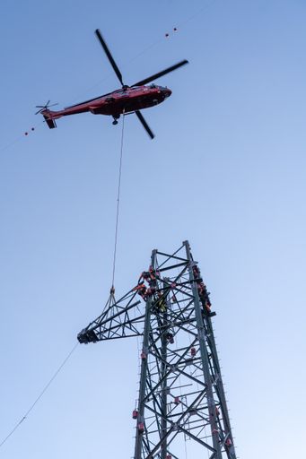 Vorschau Bild von An entlegenen Standorten unterstützen Helikopter
die so genannte "Maststockung". Hier wird ein Ausleger montiert, der
Pilot muss den Bauteil punktgenau zu den Monteuren bringen, die am
Mast warten.