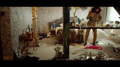 Conchita Wurst steht nach einer Partynacht in einem
verwüsteten Hotelzimmer und trinkt ein Glas. Standbild aus dem CAR
(IDHLARGT) Musikvideo von Conchita Wurst