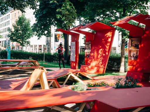 Vorschau Bild von Ausstellungsansicht von "ICH BIN DA!" am
Bischof-Reinhold-Stecher-Platz in Innsbruck. Der Entwurf von
Architekturstudierenden am Institut für Gestaltung.studio2 der
Universität Innsbruck erinnert an gefaltete Kartons, die obdachlose
Menschen mitunter als schützende Hülle einsetzen. Er dient zugleich
als Aufenthaltsort auf dem zentral gelegenen und doch
vernachlässigten Platz – und ist dabei auch Ausstellungsfläche und
Veranstaltungsraum. Entwickelt wurde das Projekt gemeinsam mit der
Tiroler Straßenzeitung 20er. Die Redaktion hat die Künstlerin Jana
Sophia Nolle als ausstellende Fotografin eingeladen. Sie
fotografiert innerhalb der Langzeit-Serie "LIVING ROOM" seit 2018
die Behausungen von obdachlosen Menschen in den Wohnzimmern der
Wohlhabenden – bisher in San Francisco und Berlin, künftig auch in
Paris und weiteren europäischen Metropolen.