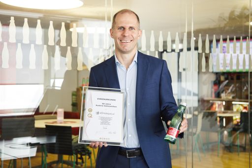  Herbert Bauer, General Manager Coca Cola HBC
Österreich, mit der Ehrenurkunde über "60 Jahre Austria Gütezeichen"
und einer Römerquelle-Flasche; Zertifizierung für Römerquelle still,
prickelnd und mild.