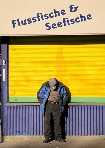 Vorschau Bild von Mann lehnt an einem Marktstand mit der Aufschrift
"Flussfische & Seefische"
