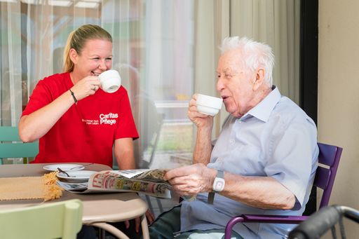 Pflegerin mit Bewohner beim Kaffeetrinken