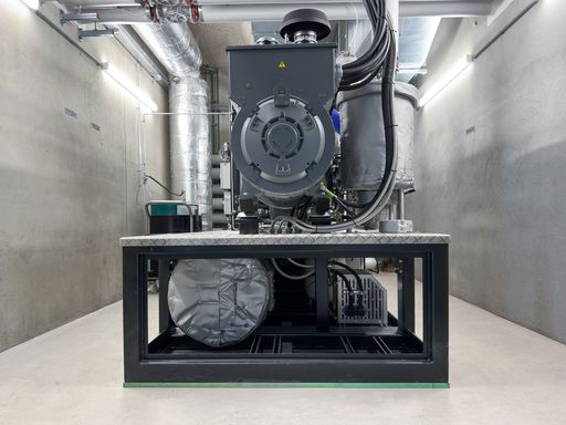 Vorschau Bild von In drei Holzvergasern findet ein thermochemischer
Umwandlungsprozess (Pyrolyse) statt, sodass Holzgas entsteht. Durch
den Motor im Blockheizkraftwerk (Bild) kann das Gas in Wärme und
Strom umgewandelt und in das öffentliche Netz eingespeist werden.