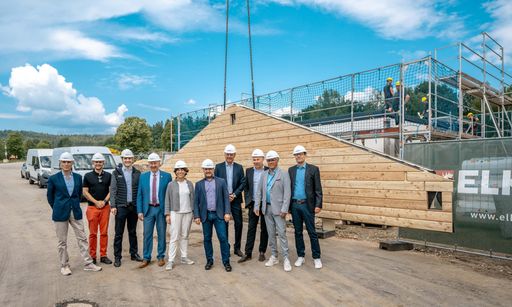  Projektverantwortliche und Firmenvertreter
verfolgten mit Landrat Helmut Plenk (ab 4. v. li.),
Vizebürgermeisterin Elisabeth Pfeffer und Bürgermeister Karl-Heinz
Eppinger die Montage des ersten Ferienhauses beim Chalet Resort
Arberland.