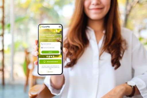  CureMe Portal Mobile Ansicht. Frau hält Smartphone in die Kamera