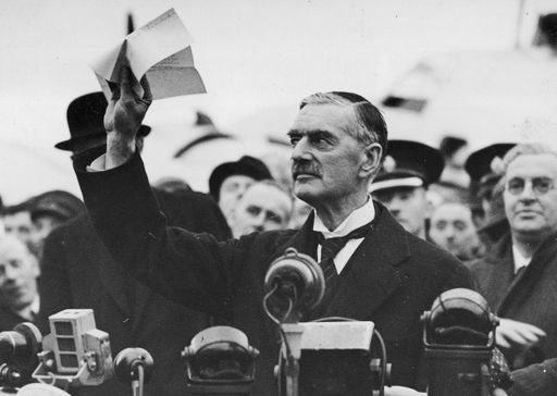  Der britische Premierminister Neville Chamberlain
zeigt unmittelbar nach seiner Rückkehr aus München auf dem Flughafen
Heston bei London die mit NS-Deutschland getroffene Vereinbarung.
(30. September 1938)