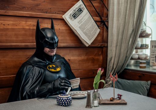 Vorschau Bild von Batman sitzt Kaffeetrinkend einem Kaffee und
genießt eine Auszeit.