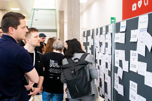  Teilnehmende des Barcamp Graz 2023, die die
Session-Wand mit Session Cards genau betrachten.
