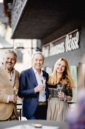 Vorschau Bild von Peter Kraus mit den Gastgebern Matthias und Benita
Hinterberger am Balkon des neuen Hotels Schwarzes Rössl am
Wolfgangsee