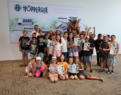 Vorschau Bild von Initiator Harald Höpperger (hinten) und Maskottchen
"Höppi" freuen sich mit den Schüler:innen über den Erfolg des
Entsorgungslehrpfades.