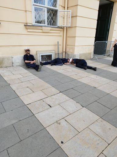 Vorschau Bild von An verschiedenen Orten liegen kleine Gruppen von
„Polizisten“ betrunken und schlafend am Boden vor dem Wiener
Museumsquartier herum.
