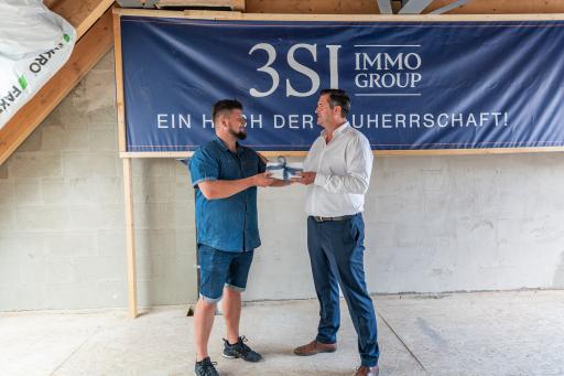 Mario Pichler, Leiter Baumanagement der 3SI Immogroup (rechts)
bedankt sich beim Bauteam und übergibt das Gleichengeld.