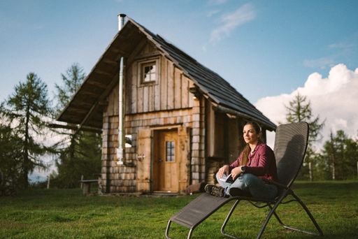  Frau entspannt im Liegestuhl vor einer Almhütte