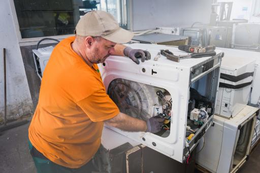 ein Mann repariert eine gebrauchte Waschmaschine