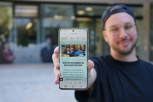  Die FH Kufstein Tirol immer in Reichweite: Ein Studierender
präsentiert die neue mobile Version der Website vor dem Campus der
FH Kufstein Tirol.