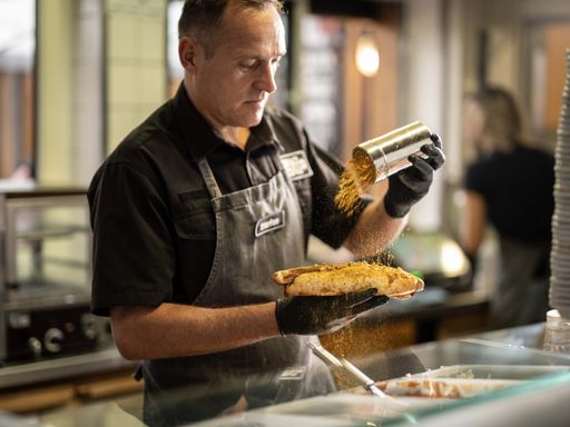Vorschau Bild von Stefan Pühringer, CEO und Gründer von Bosna Plus, streut eine
kräftige Prise vom geheimen Bosna Gewürz über die knackige XXL
Bratwurst.