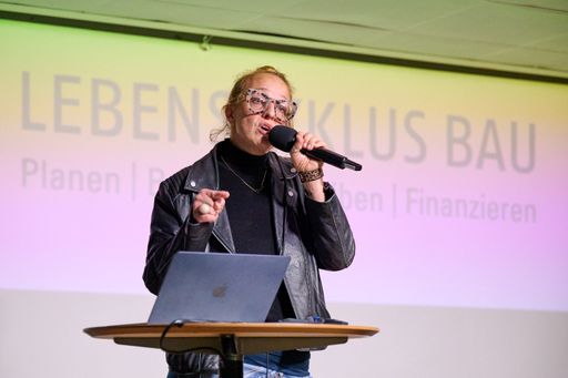 Vorschau Bild von Tiefer ging man dann in die Textilbranche: Autorin und Aktivistin
Nunu Kaller skizzierte eindrucksvoll die aktuellen Herausforderungen
der globalen Textilindustrie mit Überproduktion, Nachhaltigkeit und
Recycling und verdeutlichte die Parallelen zwischen Textil- und
Baubranche. Copyright: Leo Hagen/IG Lebenszyklus Bau