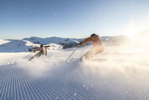  Zwei Skifahrer auf der Piste im Morgenlicht