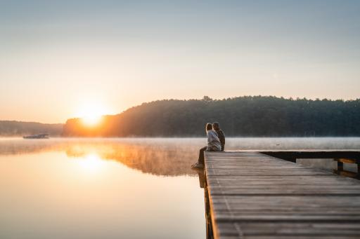  Ein Paar sitzt auf dem Steg zum Sonnenaufgang am Mirower See