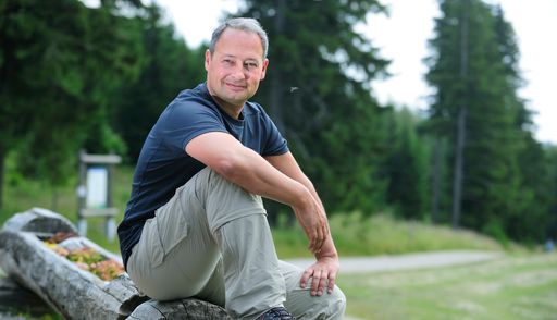  Andreas Schieder sitzt auf einem Baumstumpf in den Bergen
