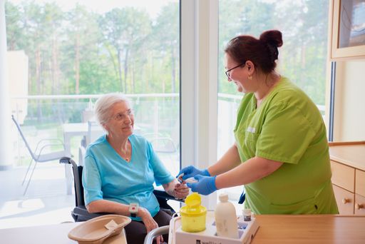 Vorschau Bild von Pflegeperson mit Bewohnerin bei der Blutzuckermessung